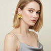 Eda Jewels Dubai gold plated ginkgo leaf flower drop earrings with a pearl accent and long fringe chains worn by a model
