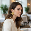 Mia large gold plated molten wavy statement stud earrings worn by a model by Eda Jewels Dubai