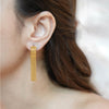 Ria gold plated hoop earrings featuring cascading monochrome gold beaded fringe worn by a model by Eda Jewels Dubai