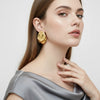 Eda Jewels Dubai gold plated smooth organic molten teardrop statement earrings worn by a model.