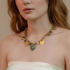 Thalassa gold plated charm necklace featuring a central blue enamel heart pendant with seashells and colorful beads worn by a model by Eda Jewels Dubai
