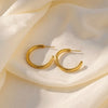 Vani classic gold plated open hoop earrings resting on draped white silk fabric by Eda Jewels Dubai