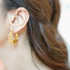 Zara gold plated chunky hoop earrings featuring a textured molten hammered finish worn by a model by Eda Jewels Dubai 