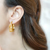 Zara gold plated chunky hoop earrings featuring a textured molten hammered finish worn by a model by Eda Jewels Dubai 